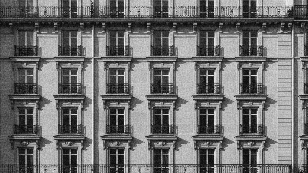 Façade d'immeuble haussmannien à balcons en fer forgé, lumière rasante de fin d'après-midi, périmètre strict de l'IFI immobilier